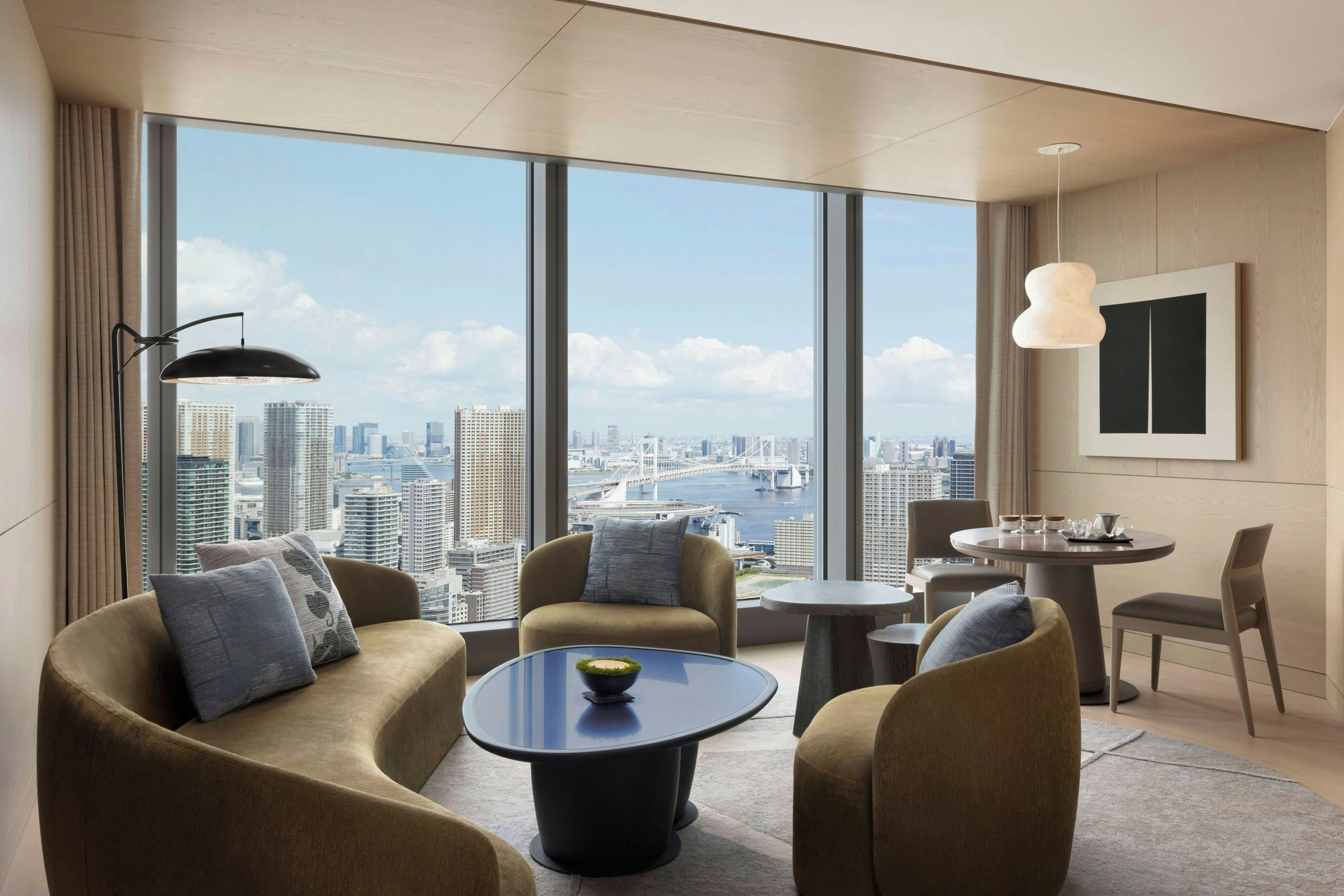 Et moderne hotelværelse med udsigt over byen, et rundt bord og to sofaer.