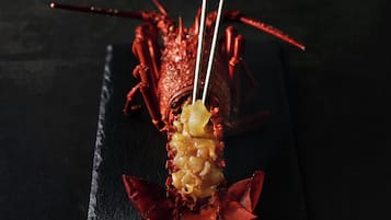 A lobster with a white sauce on a black tray.