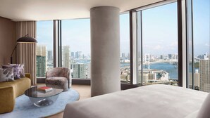A modern hotel room with a large window offering a city view, a comfortable sofa, a glass coffee table, and a large bed. - JW Marriott Hotel Tokyo (Tokyo)