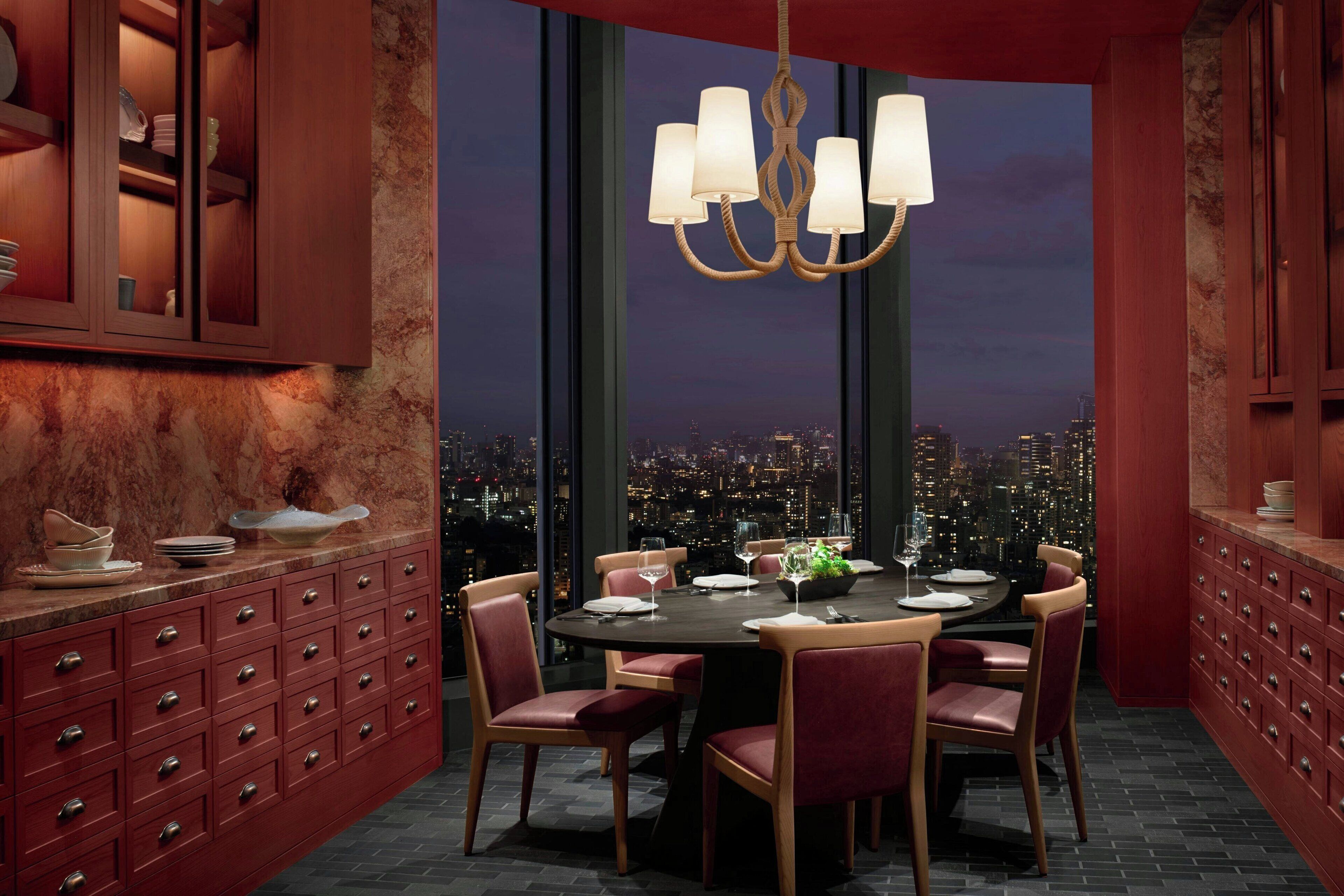 A dining area with a city view, a chandelier, and red cabinetry.