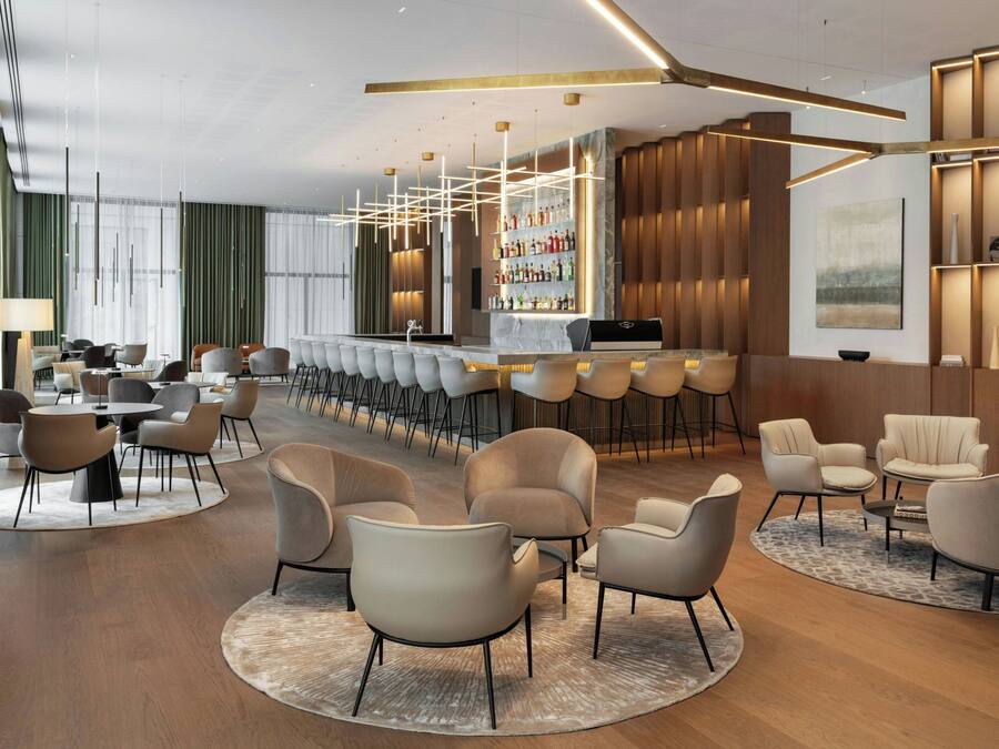Een moderne hotel lobby met een bar, zithoekjes en een groot raam dat voor natuurlijk licht zorgt.