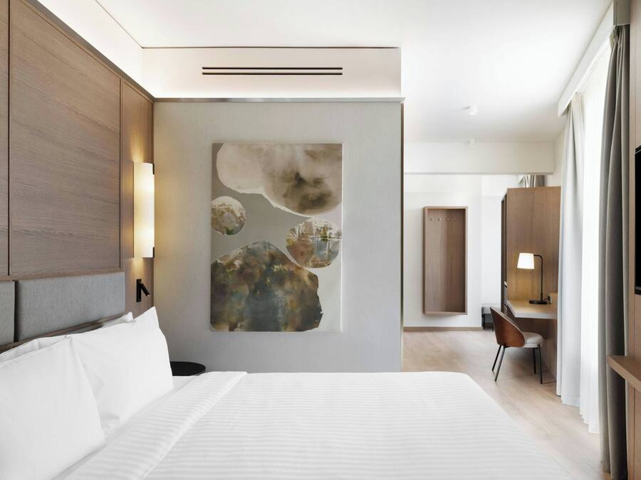 A modern hotel room with a large bed, a desk, and a TV.