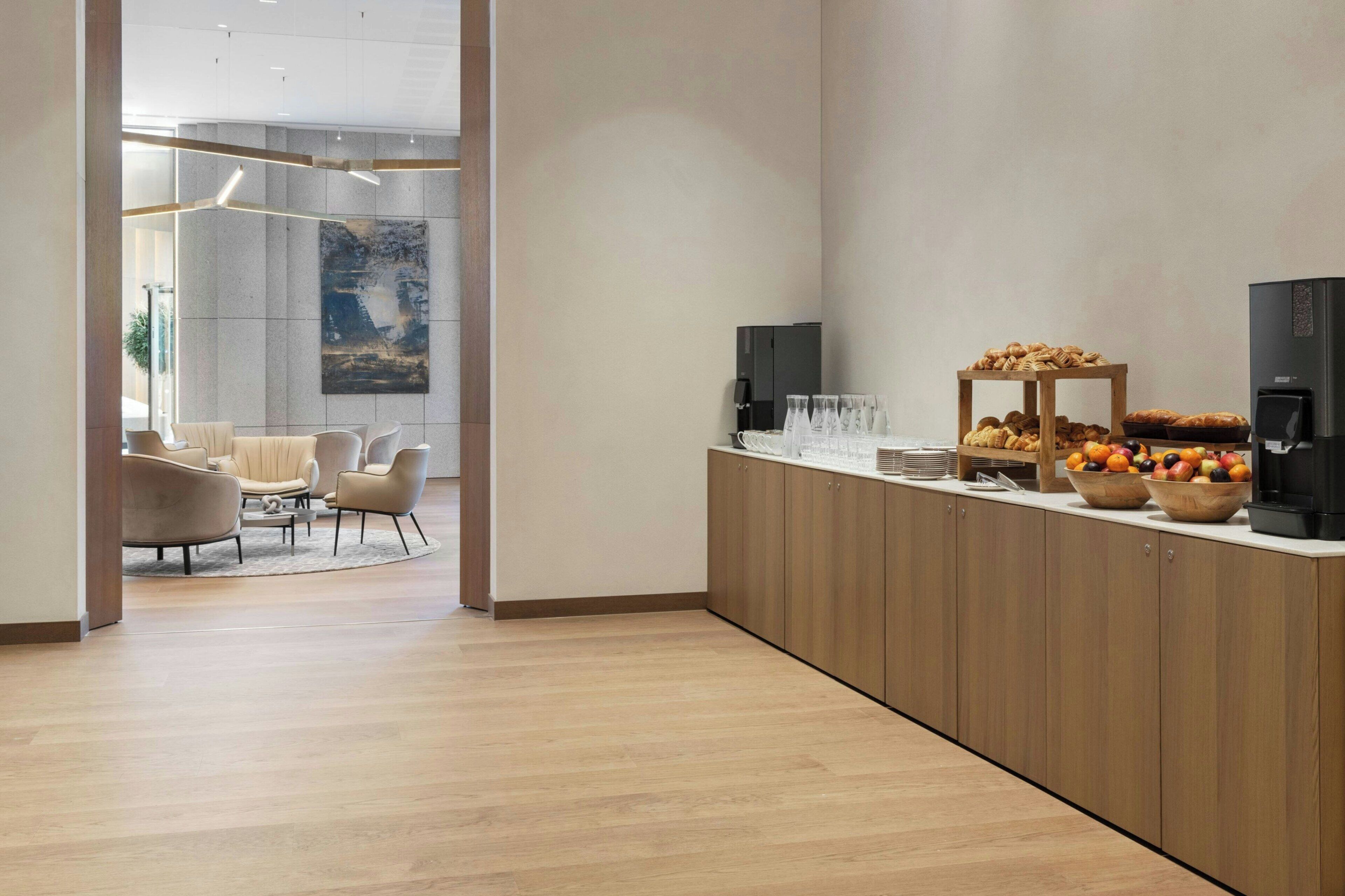 Una cocina moderna con armarios de madera, una zona de café y un espacio de estar con sillas y una mesa.