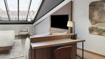 Una habitación de hotel moderna con un tragaluz grande, una cama, un escritorio, una silla y un cuadro en la pared.