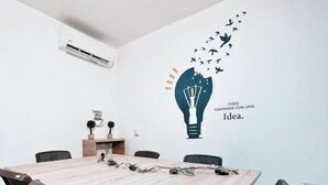 A conference room with a light bulb wall decal, a wooden table, and black chairs. - Hotel Boutique Gao (San Jose de Cucuta)