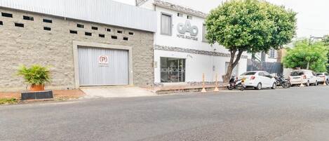 Un edificio con el letrero 'Hotel Boutique', un estacionamiento y un árbol en la fachada.