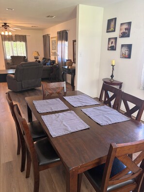 A dining area with a wooden table, four chairs, and a chandelier.