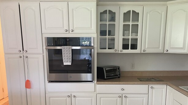 A kitchen with white cabinetry, a stainless steel oven, a toaster, and a tiled floor. - Charming 3-bedroom house . Across the street from a beautiful walking track (McAlester)