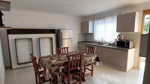Una cocina moderna con comedor, que incluye una mesa, sillas, refrigerador, microondas y hervidor.