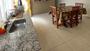 Una cocina moderna con encimeras de granito, pileta integrada y comedor con mesa y sillas.