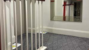 A staircase with a patterned carpet, a wooden handrail, and a wall-mounted mirror.