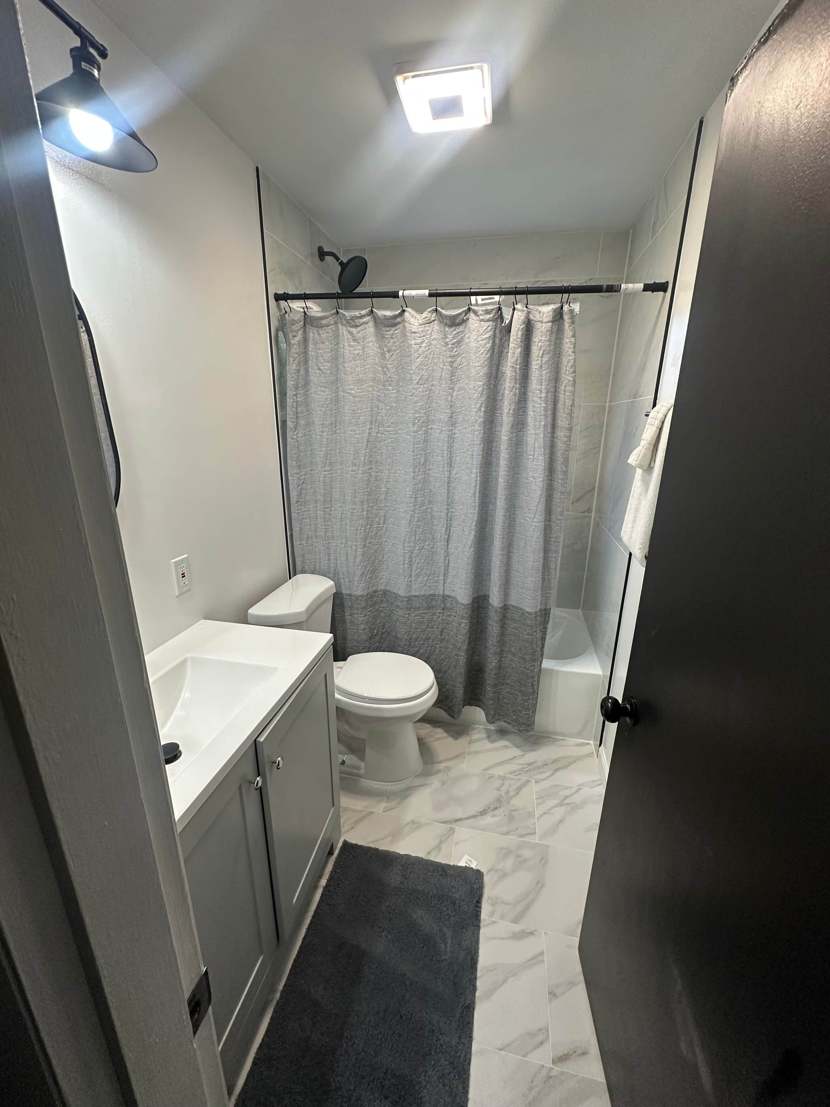 A compact bathroom with a toilet, sink, and shower curtain.
