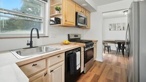 Eine moderne Küche mit Spüle aus Edelstahl, Holzschränken, einem Einbauofen und einem Kühlschrank.