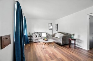 Un salon avec deux canapés, une table basse et une table d’appoint.