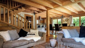 Ein gemütliches Holzinnere mit einer Treppe, zwei Sofas mit Kissen, einem Couchtisch und einem Essbereich mit Stühlen und Tisch.