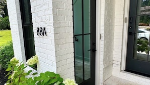 Une maison moderne avec une façade en briques blanches, une porte noire et le numéro « 88A » inscrit sur le mur.