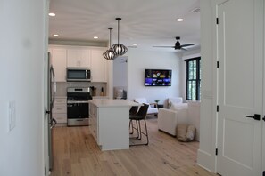 A modern kitchen with white cabinets, a large island, stainless steel appliances, and a ceiling fan. - Clean, Stylish 1 Bedroom Apartment - Minutes from Downtown Alpharetta/Avalon (Alpharetta)