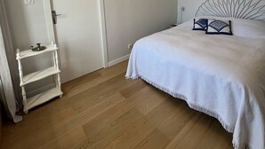 A bedroom with a bed, a bedside table, a mirror, and a door. - Two-room apartment in the Les Mielles neighborhood (ST CAST LE GUILDO)