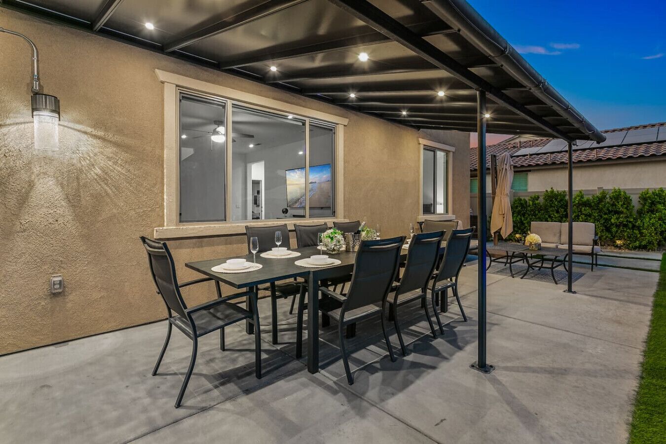 Una terrazza esterna con zona pranzo coperta, un'ampia finestra e vista sul paesaggio.
