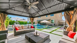 An outdoor patio with a pool, seating area, and a covered section with a ceiling fan. - 11 Beds,Pool table,Ping Pong,Volleyball+Basketball (Coachella)