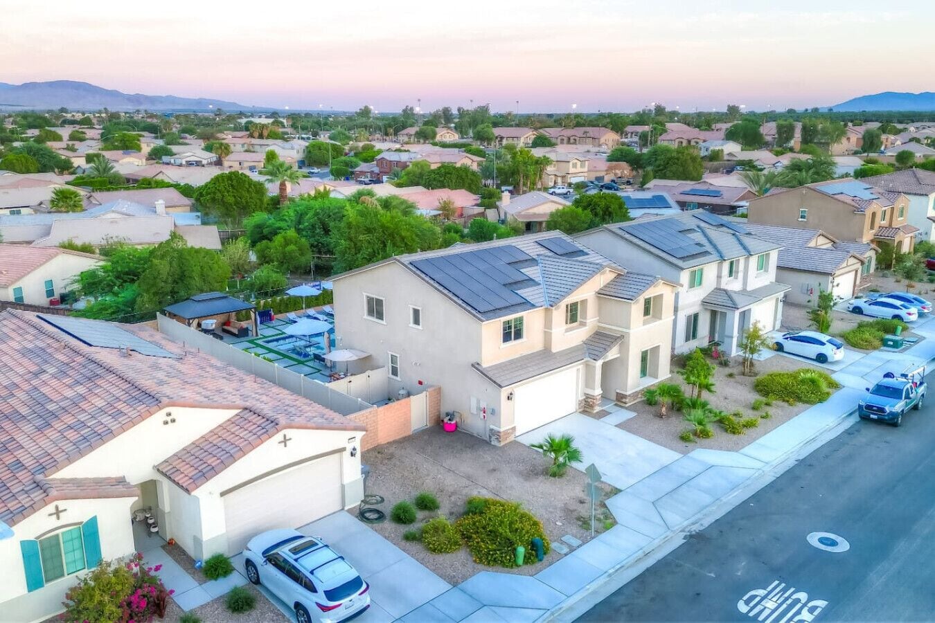 A residential area with houses, a swimming pool, and parked cars.