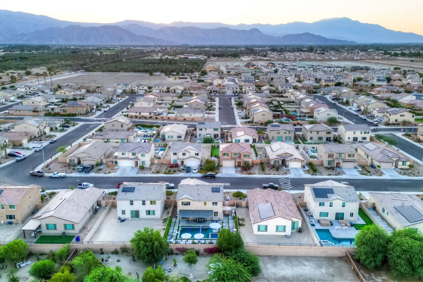 Un barrio residencial con casas, calles y montañas al fondo.