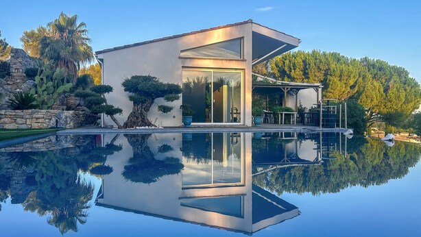 Een modern huis met een glazen deur, een zwembad en een terras.