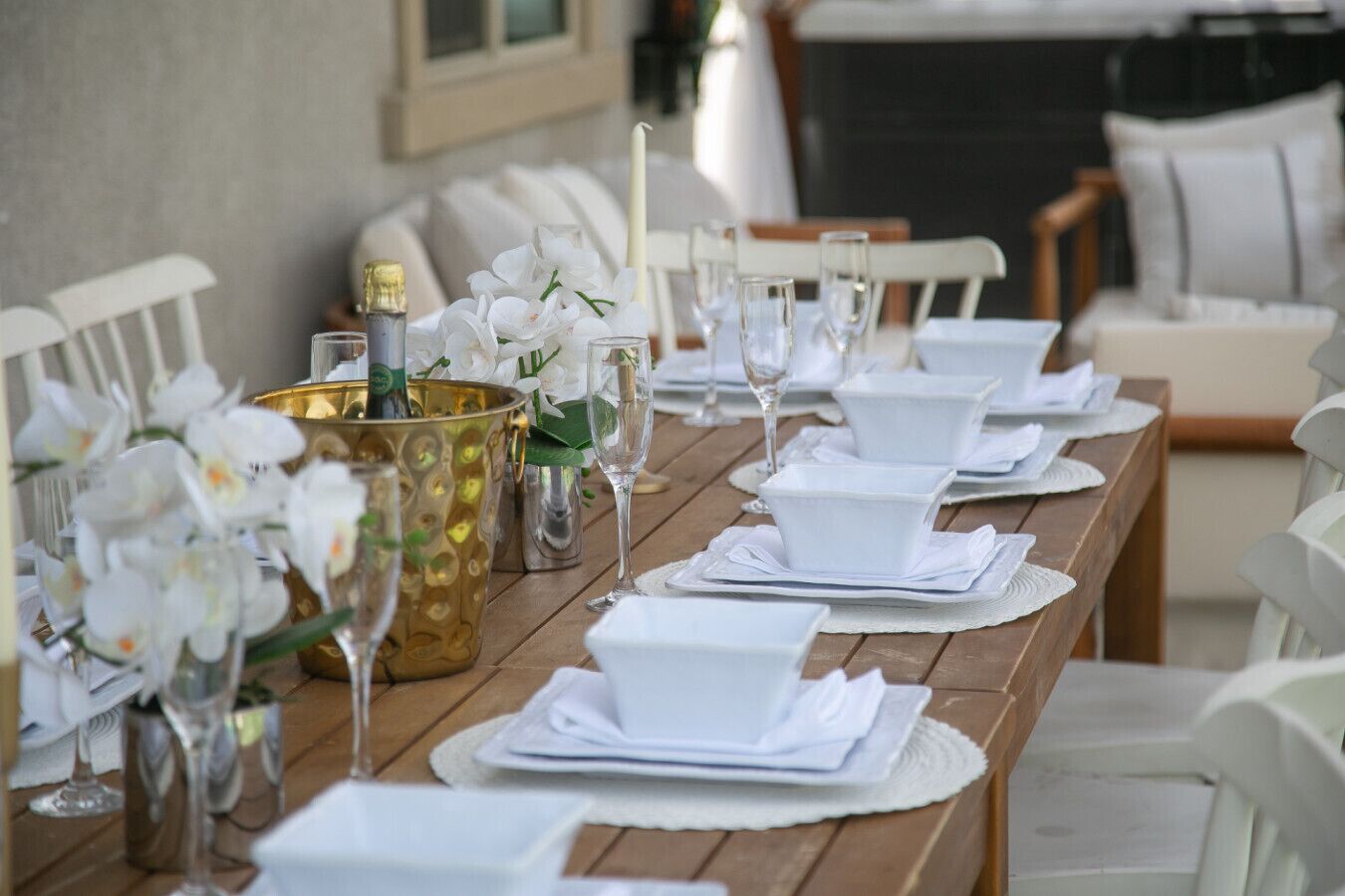 Ett vackert dukat matbord med vita tallrikar, glas och en guldfärgad ljusstake med blommor.