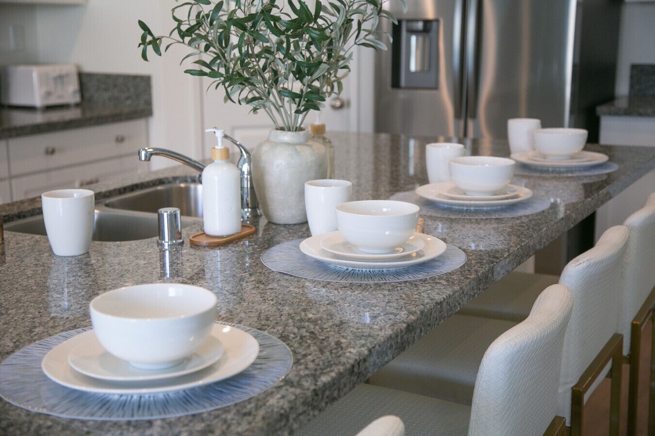 A kitchen with a granite countertop, white bowls, and a plant.