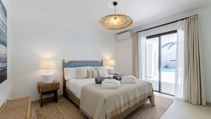 Un dormitorio con cama, lámparas de noche, una lámpara de techo tejida, vistas al exterior y una ventana con cortinas.