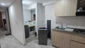 A modern kitchen with light wood cabinets, a built-in oven, and a tiled backsplash.