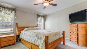 Une chambre à coucher avec un lit en bois, une commode, un téléviseur et un ventilateur de plafond.