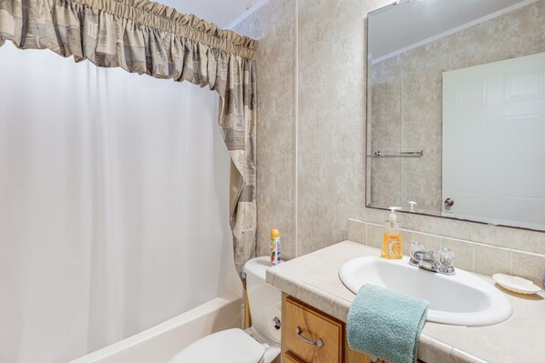 Ein Badezimmer mit Badewanne, Toilette, Waschbecken und Spiegel.