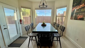A dining area with a glass-top table, four chairs, and a chandelier.