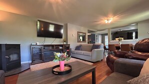 A living room with a fireplace, a television, a sofa, and a coffee table with a vase of flowers.