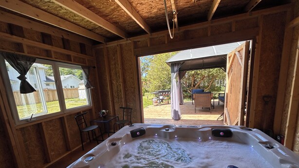 A hot tub with visible bubbles, wooden walls, and a view of an outdoor patio area.