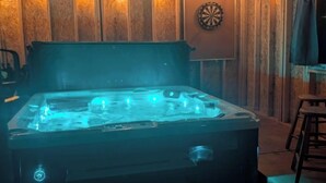 A hot tub in a wooden room with a dartboard on the wall.