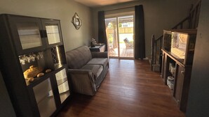 A living room with a sofa, a built-in entertainment unit, and a sliding glass door leading to a patio.