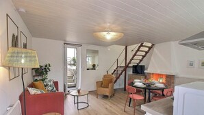 Amplia sala de estar con escalera, una mesa de comedor para cuatro personas y una zona de cocina.