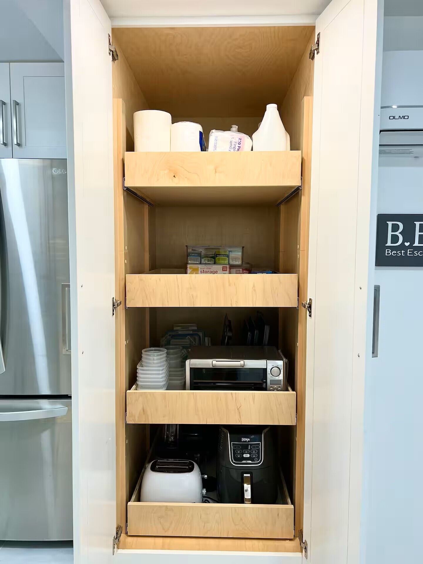A kitchen pantry with open shelves containing storage boxes, a toaster, a rice cooker, and a microwave.