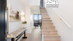 A modern interior with a marble bench, a framed picture of a bull, and a staircase leading to a balcony with a view.