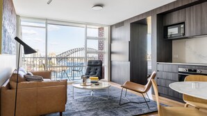 A modern living room with a sofa, a coffee table, and a view of the Sydney Harbour Bridge.