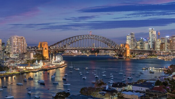 A cityscape with a prominent bridge, numerous boats, and a waterfront area.