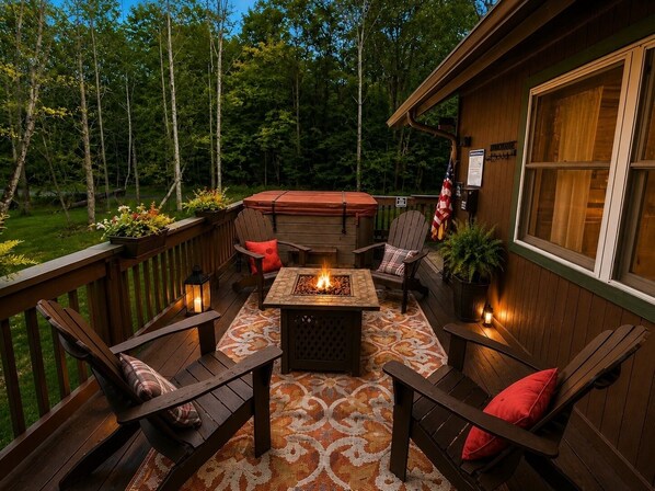Eine Terrasse mit Feuerstelle, Sitzgelegenheit und Whirlpool.