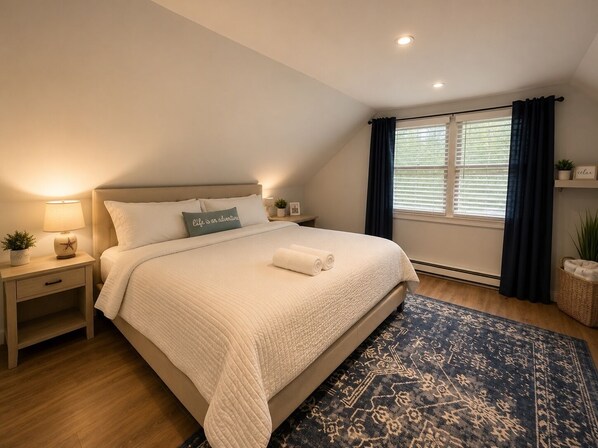 Une chambre à coucher avec un lit, des tables de chevet, une lampe, une fenêtre avec des rideaux et un tapis.