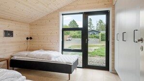 Un dormitorio con cama, armario y una puerta corrediza de vidrio que da a un jardín.