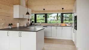 Una cocina moderna con armarios blancos, una isla grande y vistas al exterior.