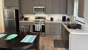 Une cuisine moderne avec des meubles gris, des appareils en acier inoxydable et un îlot central agrémenté d’un set de table à rayures.