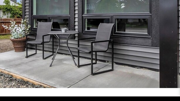 Un espace extérieur aménagé avec deux tables et quatre chaises, un pot de fleurs et une vue sur un quartier résidentiel.