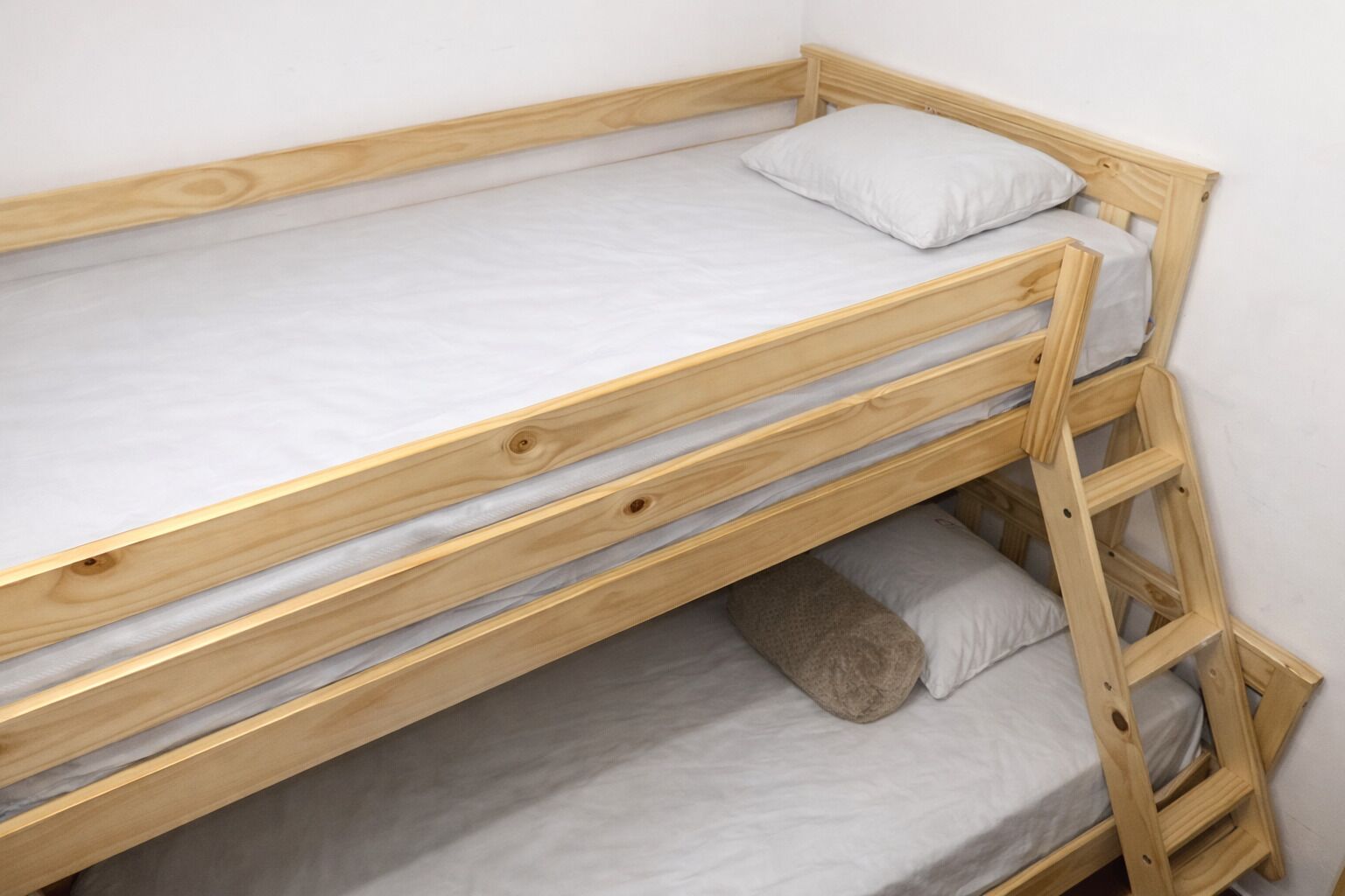 A bunk bed with a wooden frame, two pillows, and a blanket.